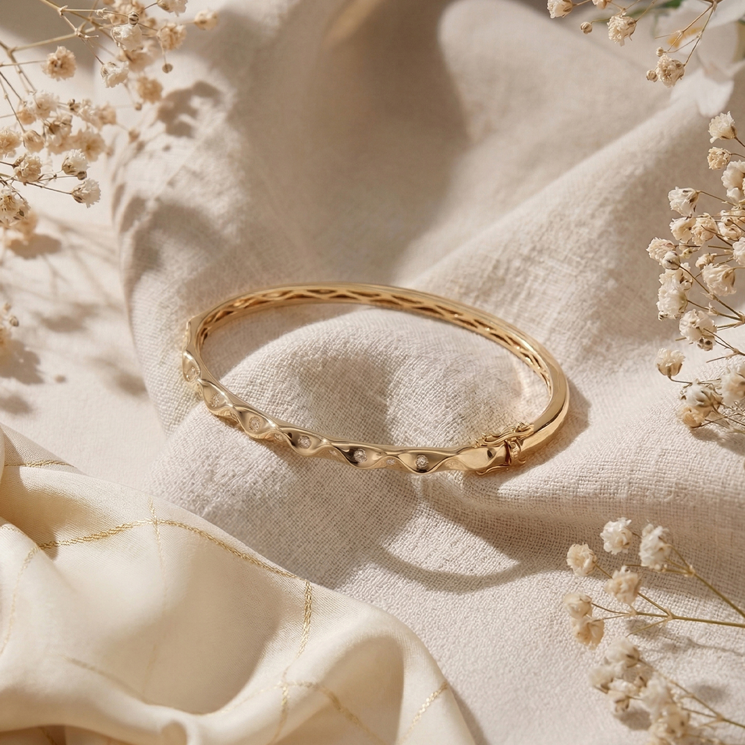 Gold and diamond bangle arranged on ivory fabric